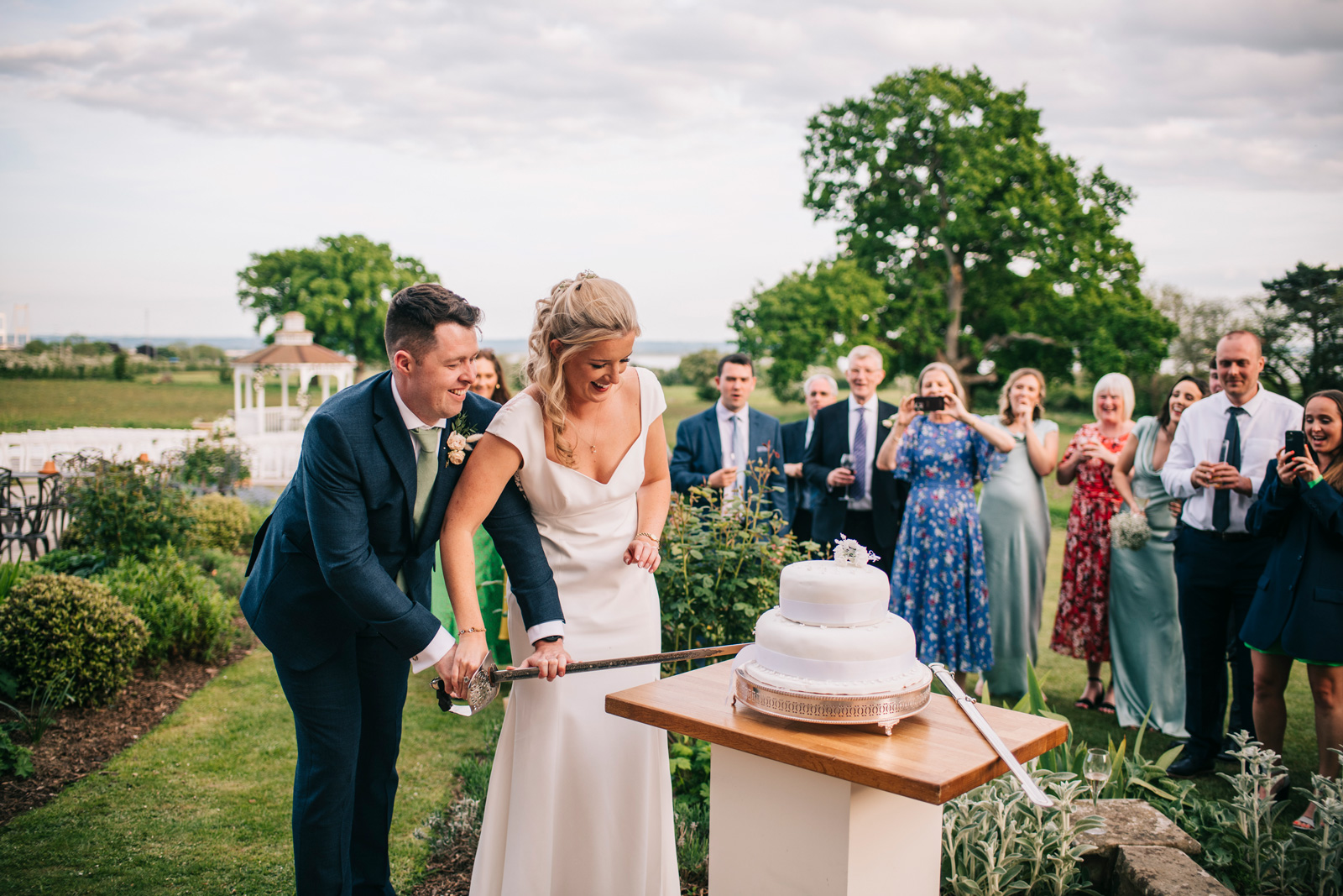 A bride and groom cutting a wedding cake outside