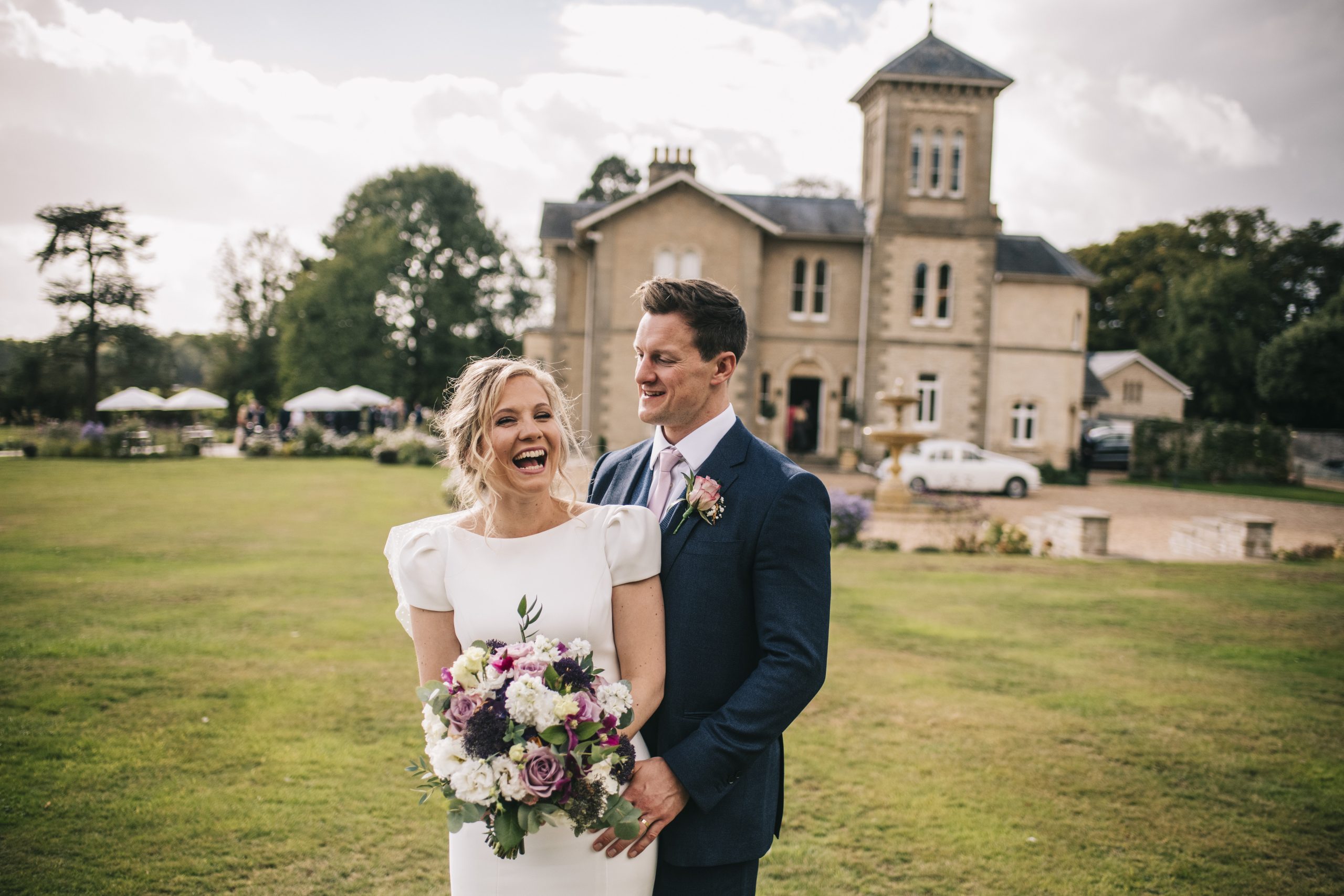 Bride and groom laughing holding flowers